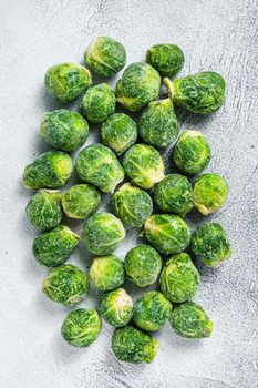 Frozen Brussels sprouts green cabbage on kitchen table. White background. Top view.
