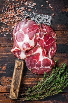Coppa, Capocollo, Capicollo Cured ham on meat cleaver. Dark wooden background. Top view.