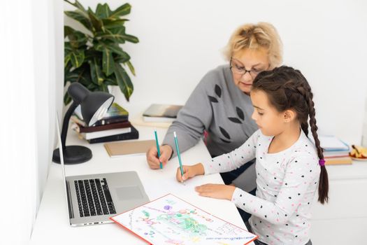 Helpful granny. Helpful loving granny assisting her cute granddaughter making homework