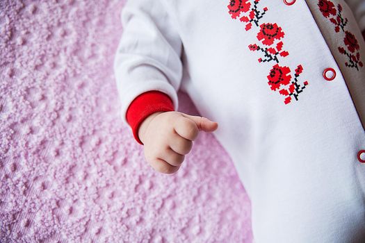 Newborn baby dressed in national costume with embroidery