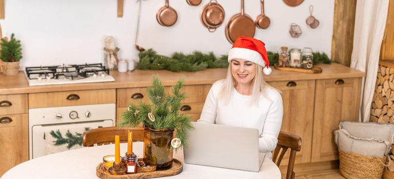 Happy woman looking in laptop in front of Christmas interior