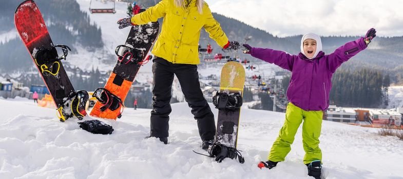 Mother and daughter with snowboards are playing in the snow