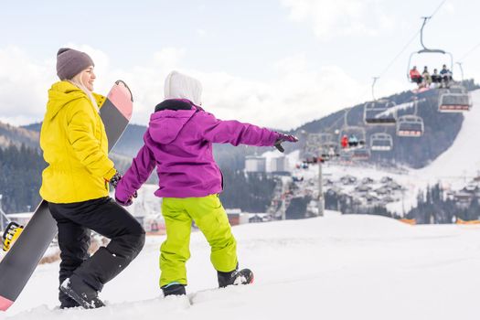 Mother and daughter with snowboards are playing in the snow