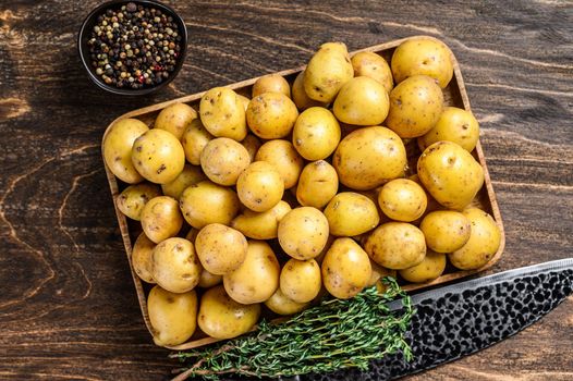 Young whole baby Potatoes in a wooden tray. Wooden background. Top view.