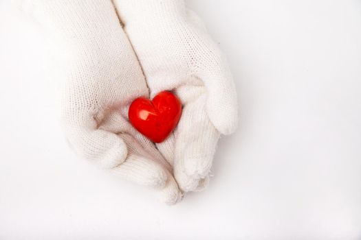 Woman hands in white gloves holding red heart symbol