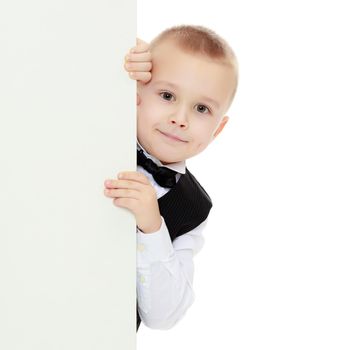 Beautiful little boy in a strict black suit , white shirt and tie.Boy peeping over white banner.Isolated on white background.