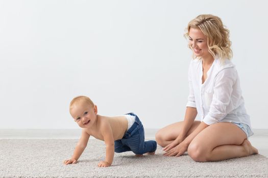 Family and parenting concept - Cute baby playing with her mother on beige carpet.