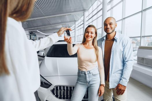 Car saleswoman in a car dealership having a talk with clients buyers