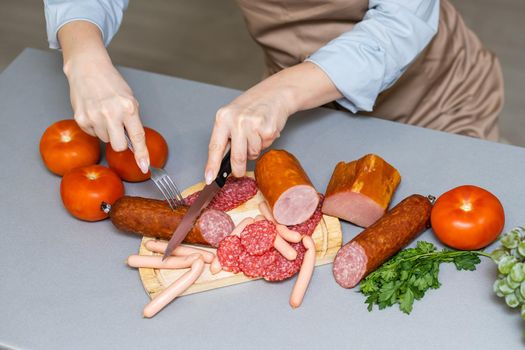 Hand closeup cuts salami with slice pieces at table