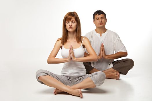 Young healthy couple in yoga position on white background