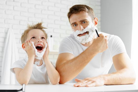 Father and little son having fun with shaving foam in bathroom