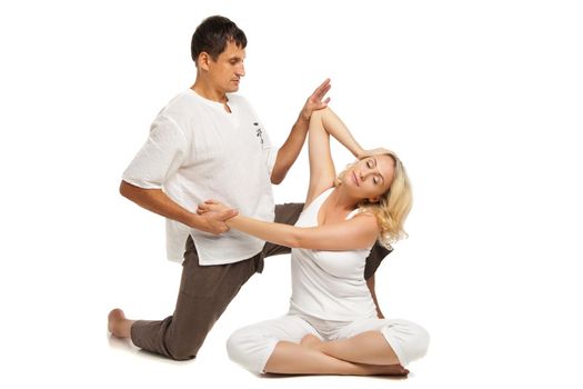 Young female sitting and receiving traditional thai arm stretching massage by therapist, isolated on white