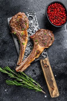 Barbecue grilled lamb chops on a butcher meat cleaver. Black background. Top view.