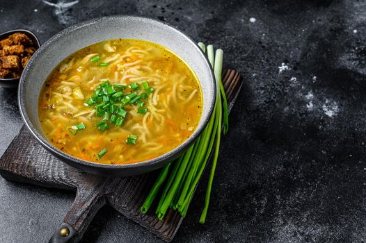 Fresh homemade chicken soup with noodle at table. Black background. Top view. Copy space.