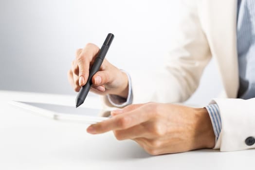 Man in business suit using tablet computer. Close-up of male hands holding pen and tablet gadget. Businessman at workplace in office. Business occupation and mobility, internet smart technology in job