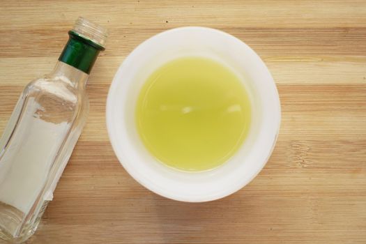 olive oil in a bowl and empty bottle on table .