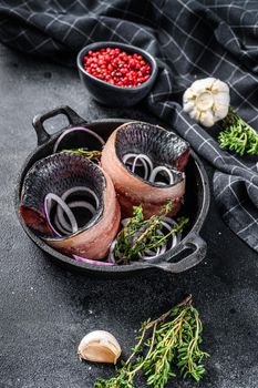 Fillet of Pickled herring with onion and thyme. Black background. Top view