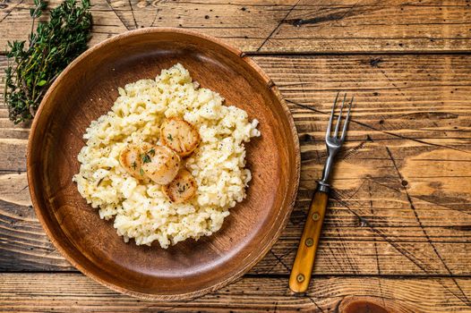 Italian Risotto with Scallops in a pan. wooden background. Top view. Copy space.