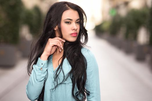 Portrait of hispanic young woman wearing casual clothes in urban background