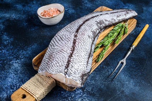 Fresh Raw grenadier macrurus white fish on a wooden cutting board. Blue background. Top view.