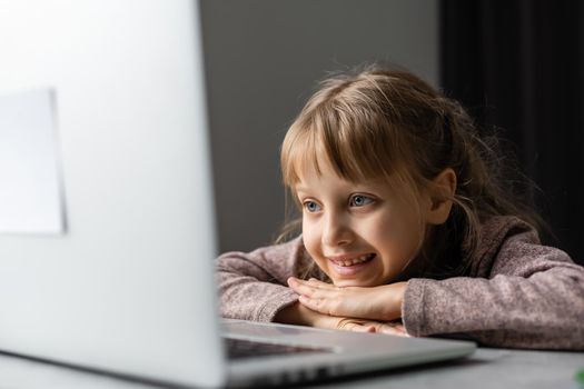 Little girl studying online using her laptop at home