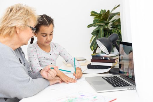 Helpful granny. Helpful loving granny assisting her cute granddaughter making homework