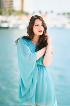 Beautiful young woman with blue eyes wearing blue dress in the beach.