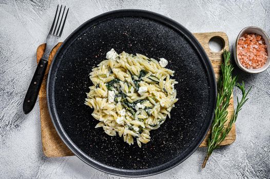 Spinach and Feta orzo pasta on a plate. White background. Top view.