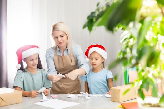 woman and two daughters carve snowflakes for christmas. Technology and Education Caucasian Blonde Family concept