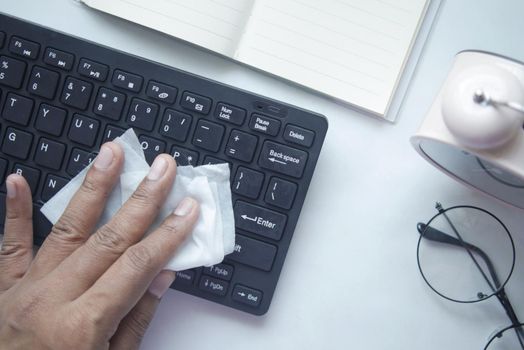 disinfecting keyboard with a white tissue on table .