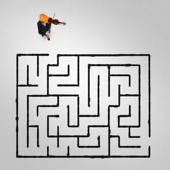 Top view of businesswoman playing violin and drawn labyrinth on floor