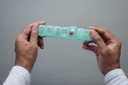 man's hands taking medicine from a pill box .