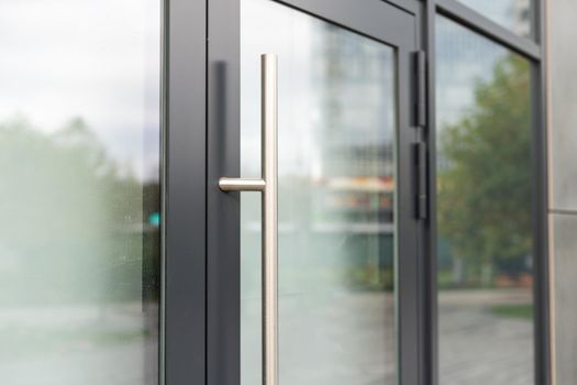 The front door of a office block, reflecting buildings in the glass.