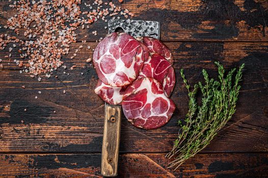 Coppa, Capocollo, Capicollo Cured ham on meat cleaver. Dark wooden background. Top view.