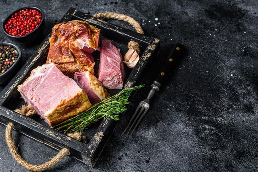 Smoked Sliced Pork Slab Bacon Meat in a wooden tray. Black background. Top view. Copy space.