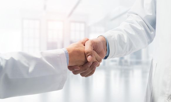 Close-up of the handshake between the two medics. Against the backdrop of the office