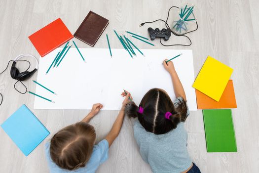 two little girls learn while lying on the floor. Education