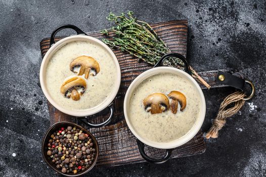 Champignon Mushroom cream soup with herbs in a bowl. Black background. Top view.