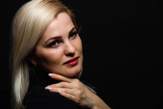Close-up portrait of beautiful model with long blond hair on black background