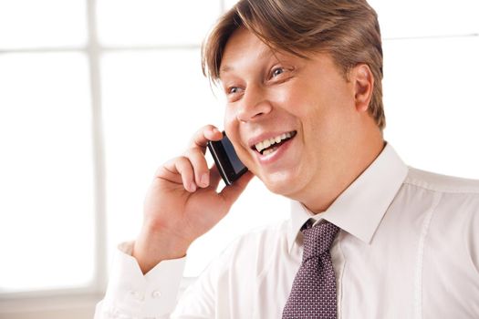 Close up of a laughing businessman on the phone in his office