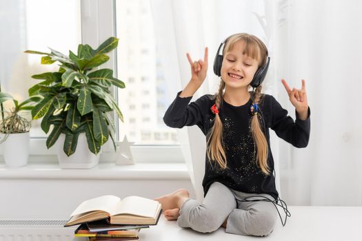 kid girl with blond hair in headphones listens to music. the social distance. quarantine and epidemic.