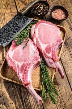 Fresh raw pork loin chops with pepper and salt. wooden background. Top view.