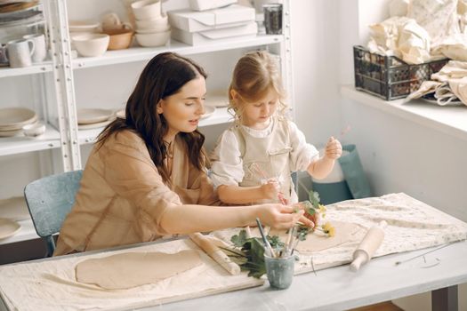 Woman and girl kneading clay. Family make art product at table in pottery workshop. Mother with daughter.