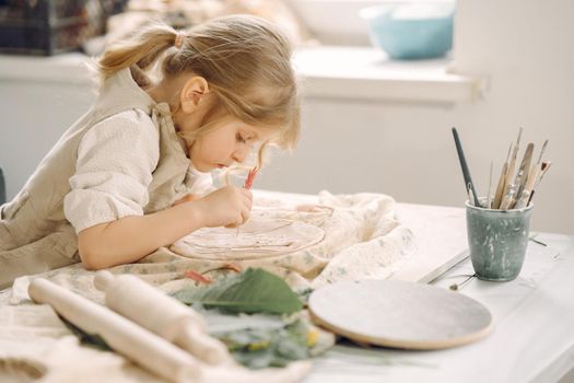 Portrait of little girl painting a ceramic model at school. Concept for art and creative education. Kids concept hobby.