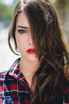 Close-up portrait of young woman with beautiful blue eyes wearing plaid shirt. Woman with long hair.