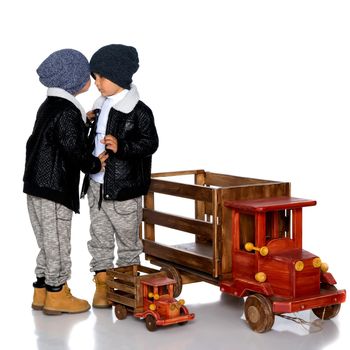 Two little boys play with wooden cars. In autumn jackets and hats. Isolated on white background.