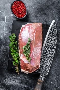 Raw duck breast fillet on a marble board. Black background. Top view.