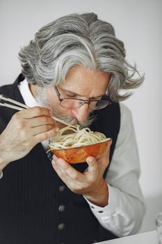 Lunch break. Elegant man in office. Businessman in white shirt. Man eats noodles.