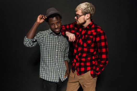 Studio lifestyle portrait of two best friends hipster boys going crazy and having great time together. On black background. Belt portrait