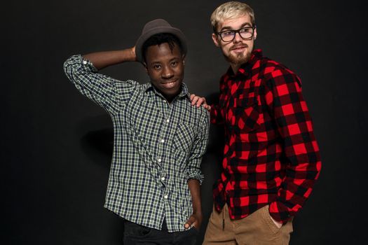 Studio lifestyle portrait of two best friends hipster boys going crazy and having great time together. On black background. Belt portrait